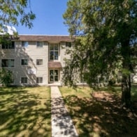 an exterior view of a house with a yard and trees