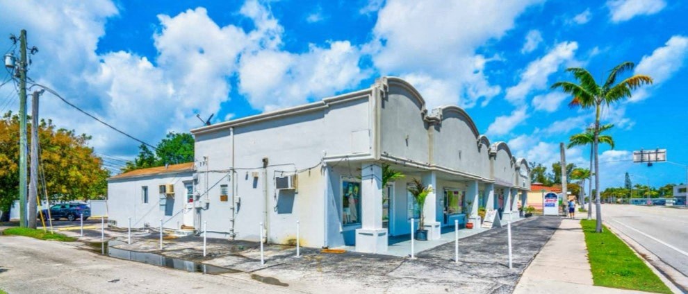 A white building with blue trim is on the corner of a street.