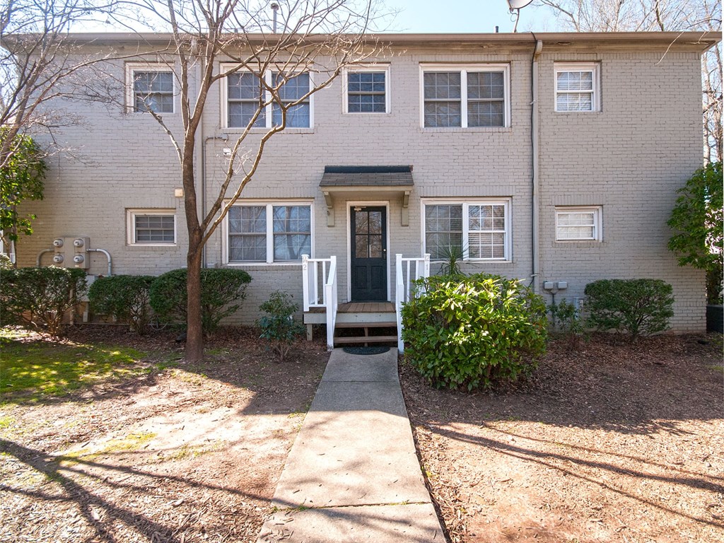 the front of a white brick house with a sidewalk in front of it