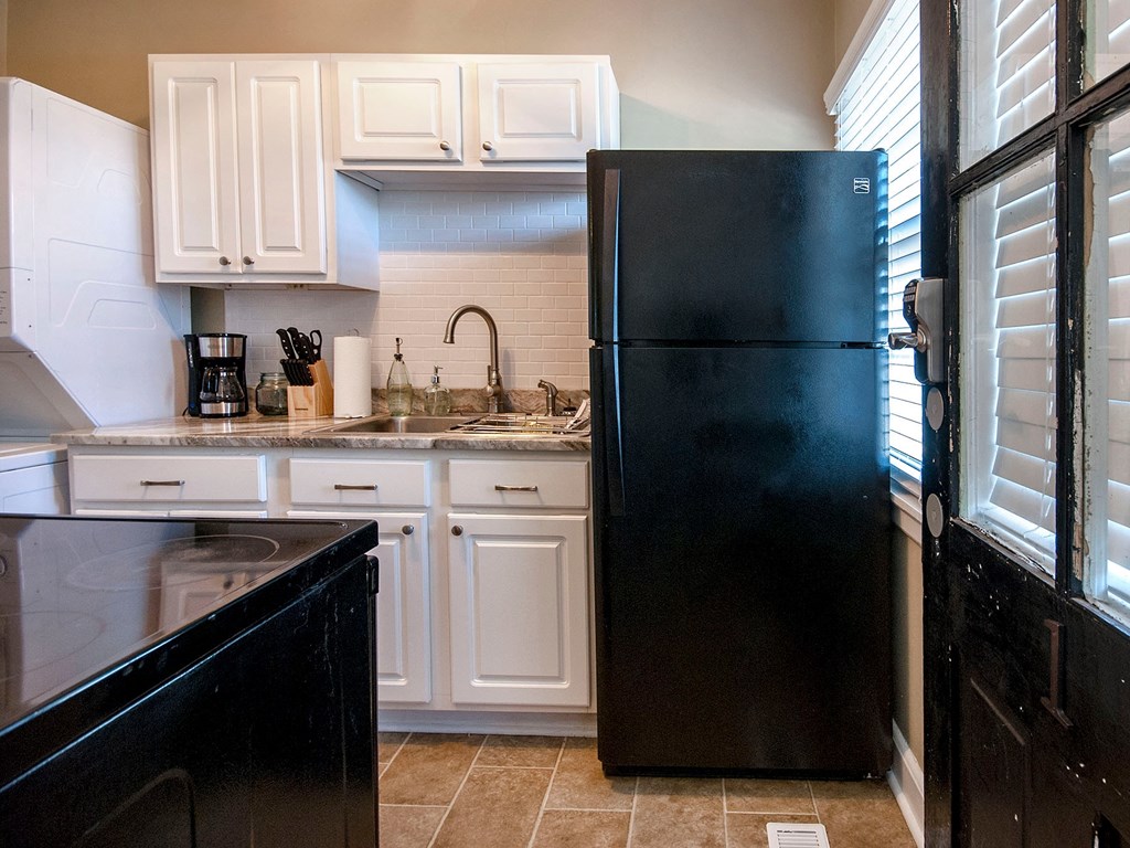 a kitchen with white cabinets and a black refrigerator