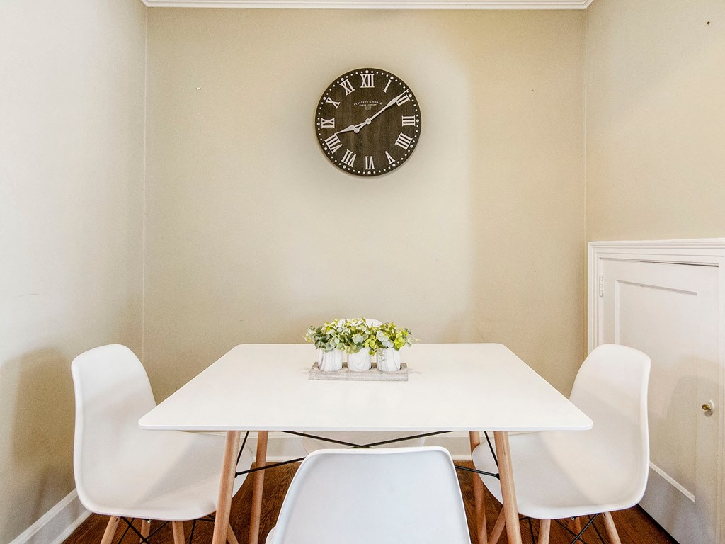a dining room with a table and chairs and a clock on the wall