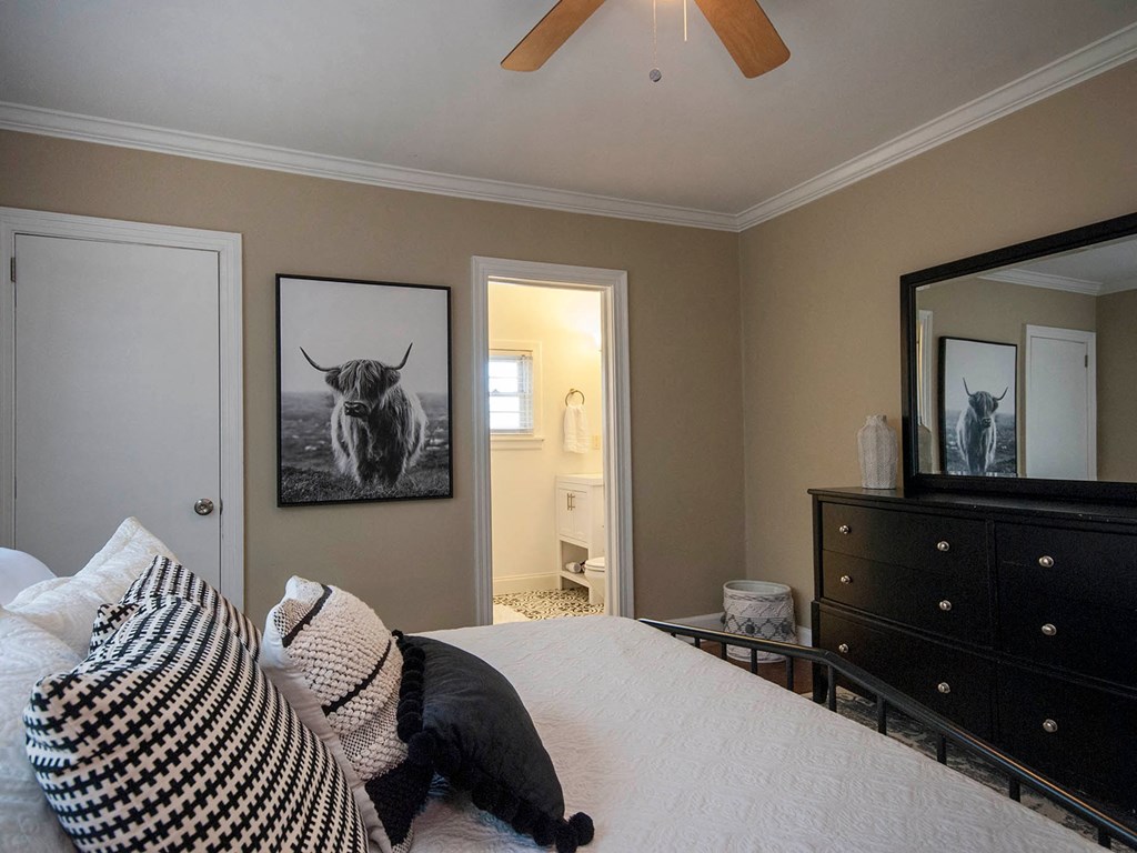 a bedroom with a bed and a dresser and a picture of a bull