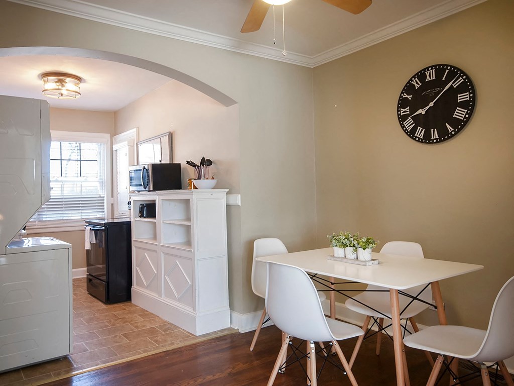 a dining room with a table and chairs and a clock on the wall