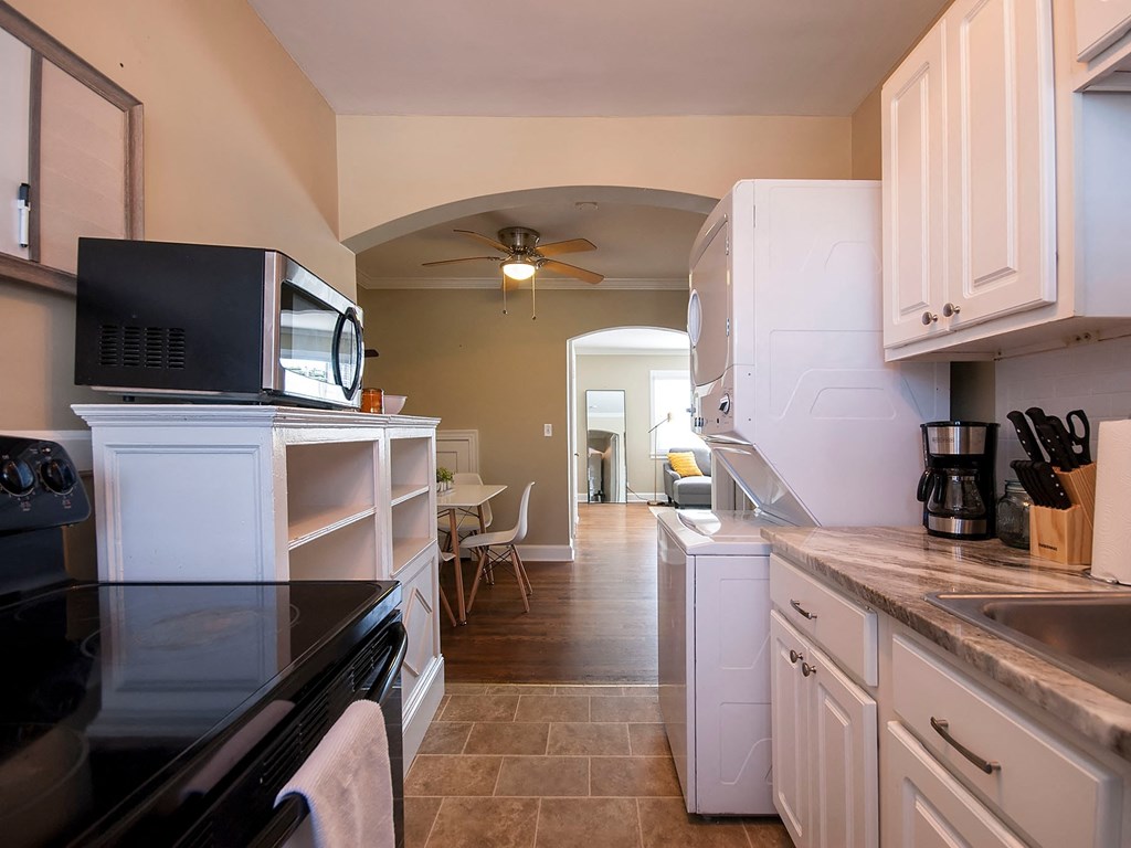 a kitchen with white cabinets and a black counter top