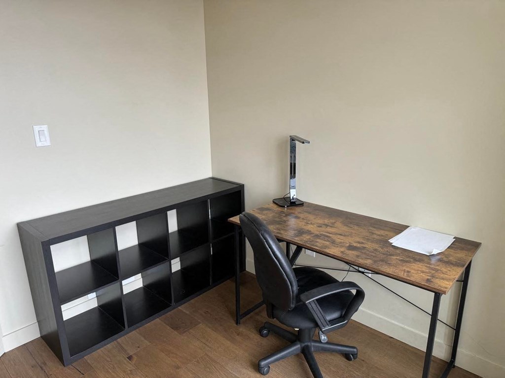 a desk with a computer and a chair in a room