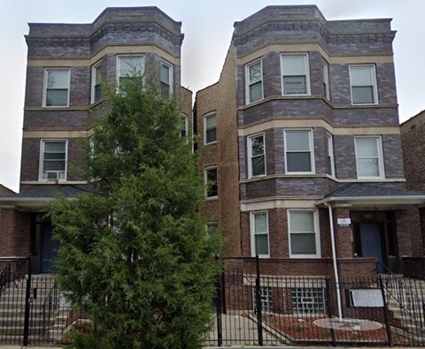 A tree is in front of a two-story brick building.