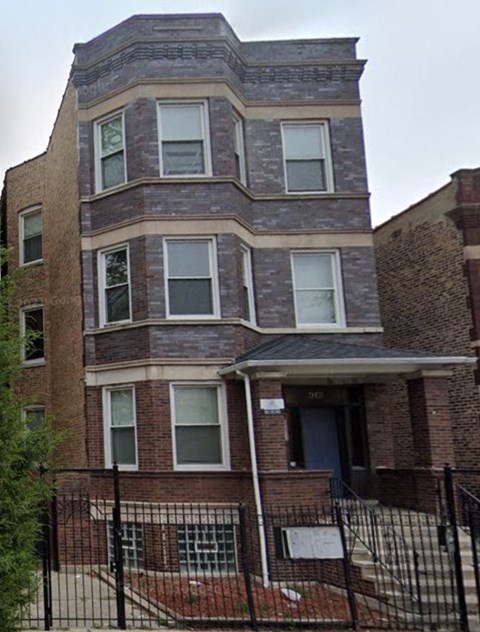 A brick building with a black fence in front.