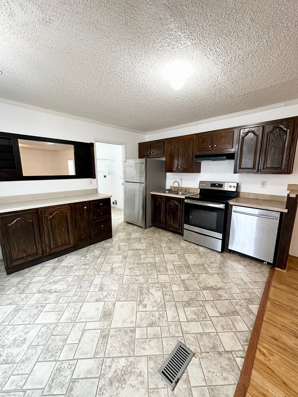 an empty kitchen with wooden cabinets and stainless steel appliances