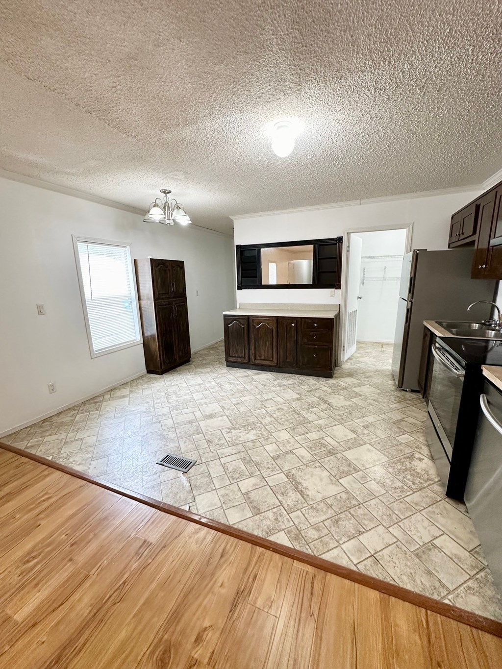 an empty living room and kitchen with wood flooring
