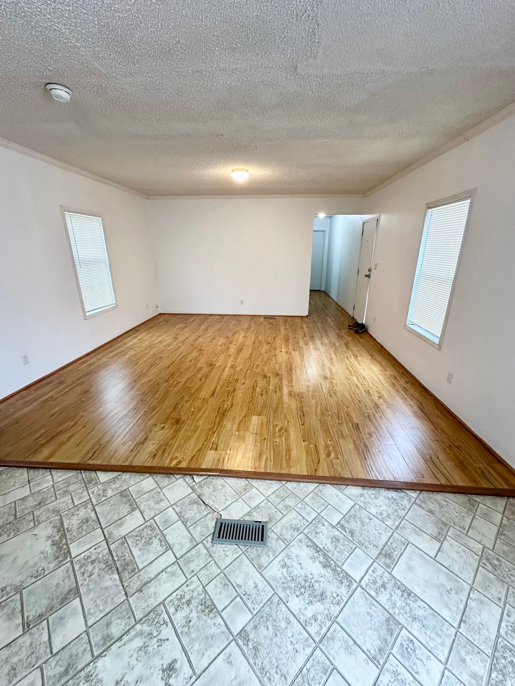 the living room and dining room of an empty house with wood floors and white walls