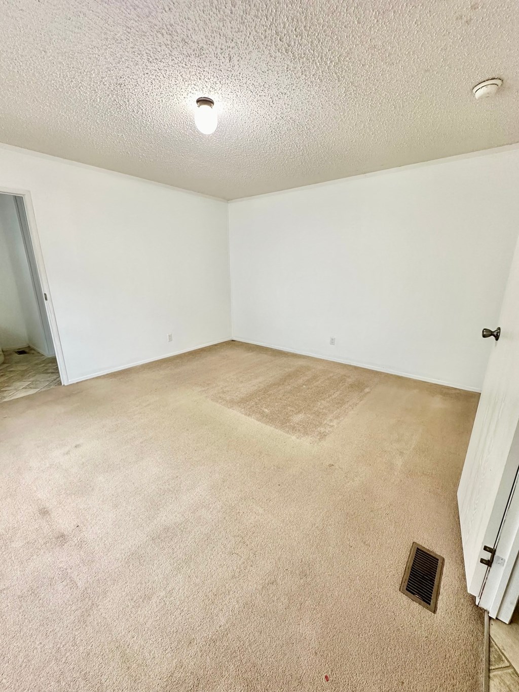 an empty living room with carpet and white walls