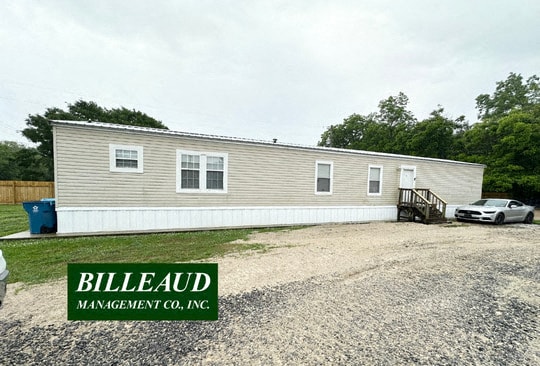 a house with a gravel driveway and a car in front of it