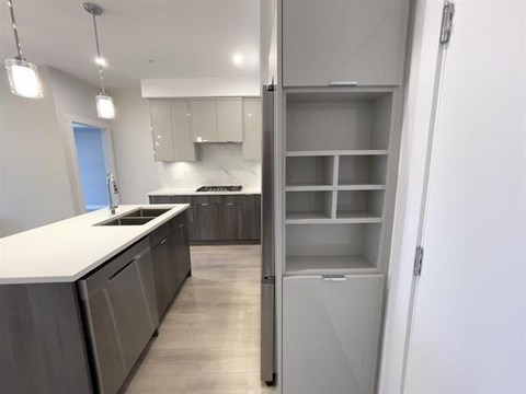 A kitchen with a white counter top and grey cabinets.