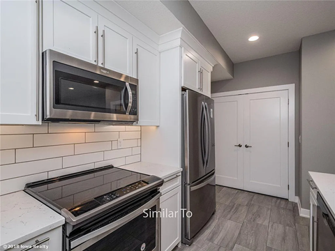 A modern kitchen with a stainless steel refrigerator, microwave, and oven.