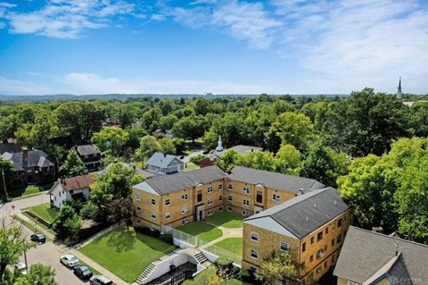 an aerial view of a brick building with a church in the background