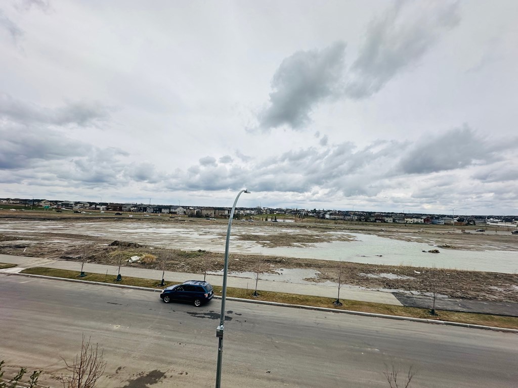 a car driving on a road next to an empty field