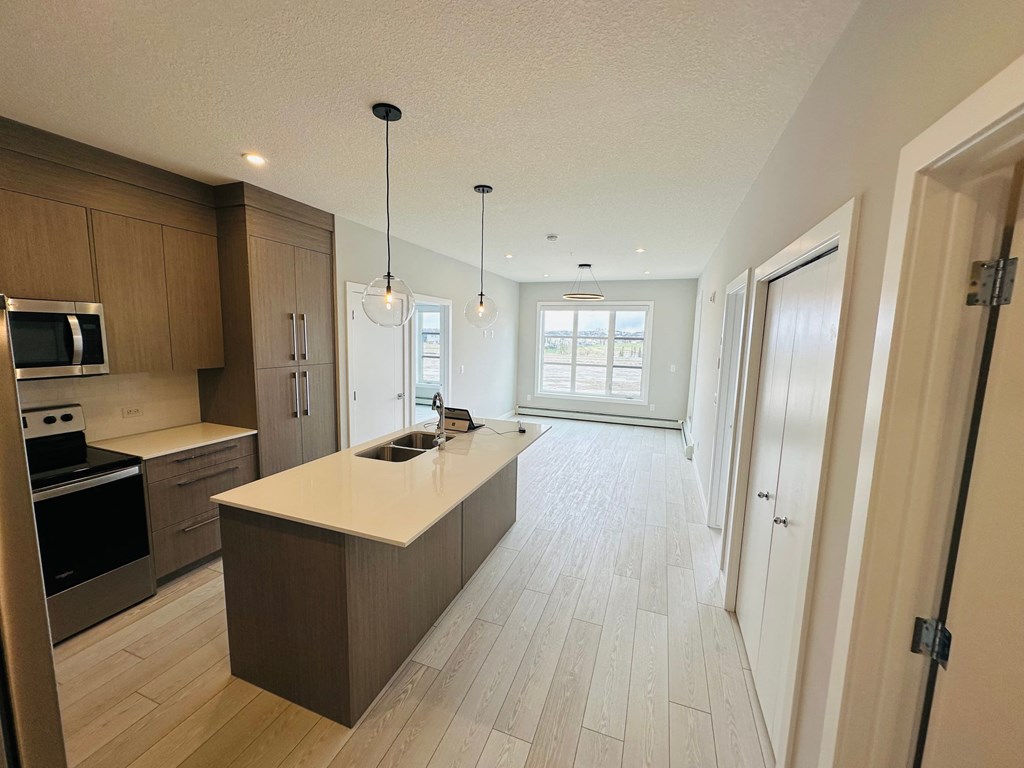 an open kitchen and hallway with wooden floors and a white counter top