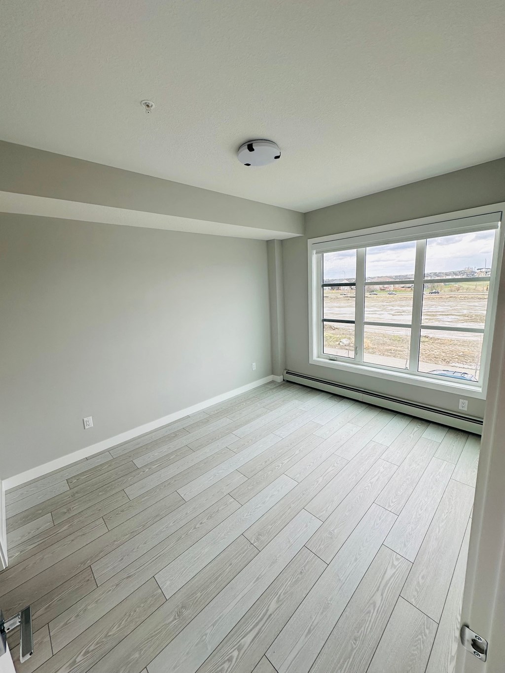 an empty living room with wood floors and a large window