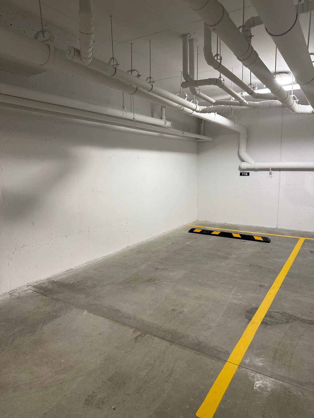a parking garage with white walls and a yellow line on the floor