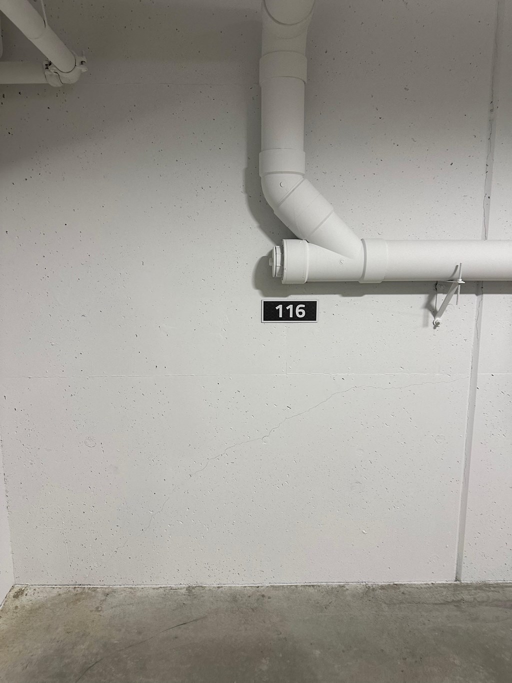 a pipe in a white wall with the number 118 on it
