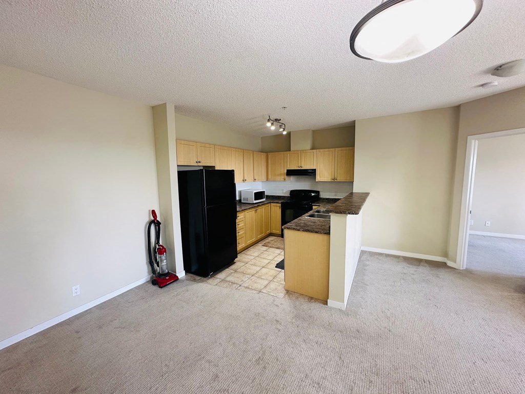 a kitchen with a stove and a refrigerator in a empty room