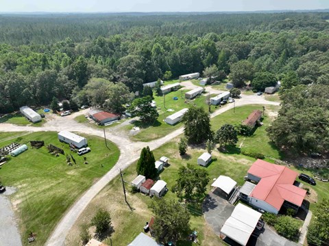A bird's eye view of a rural area with buildings, trees, and a road.