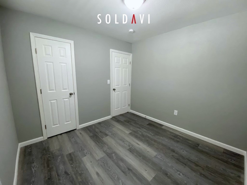 A room with two doors and a wooden floor.