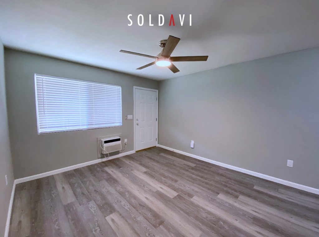 A room with a ceiling fan and wooden flooring.