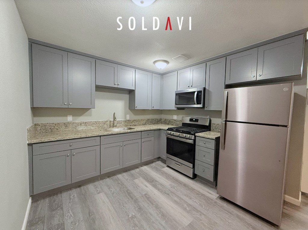 A kitchen with a refrigerator, oven, and microwave.