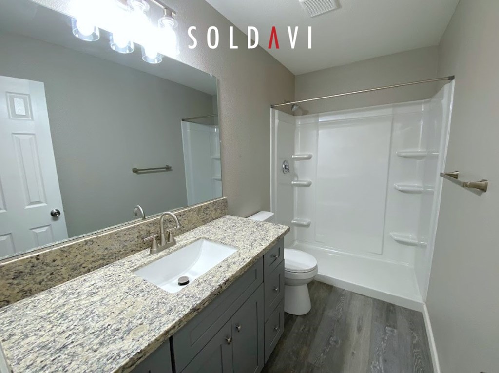 A bathroom with granite countertops and a walk-in shower.