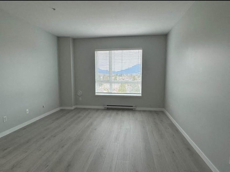 an empty room with a window and wooden floors