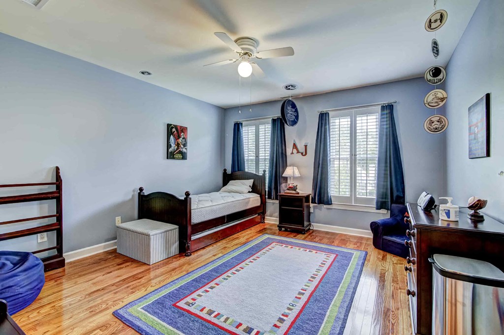 a bedroom with a bed and a desk and a ceiling fan