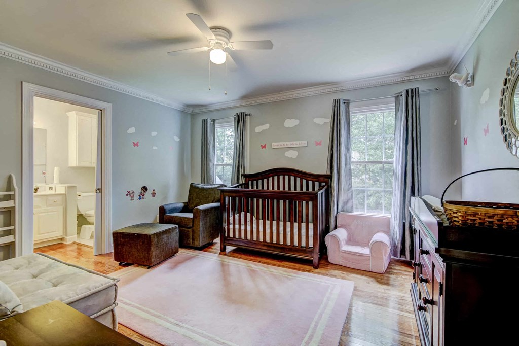 a nursery with a crib in a living room with a ceiling fan