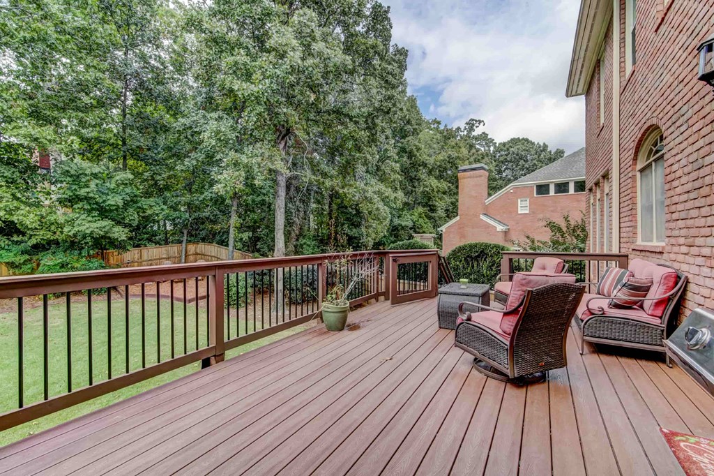 a large deck with furniture and a brick house