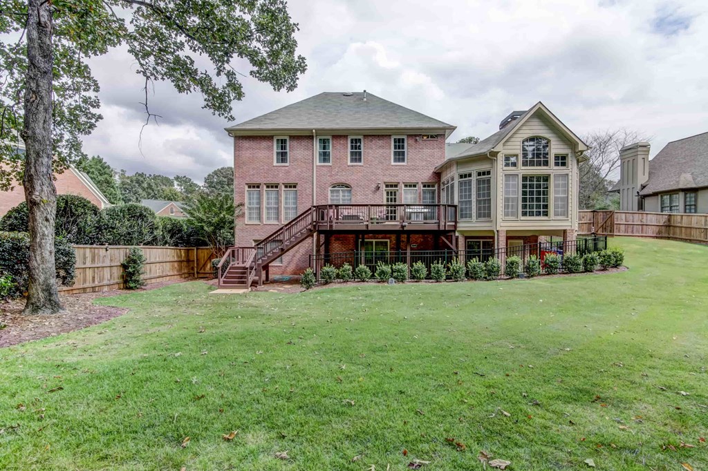 a pink brick house with a yard and a wooden fence