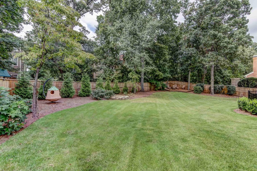 a backyard with a yard and a fence and trees