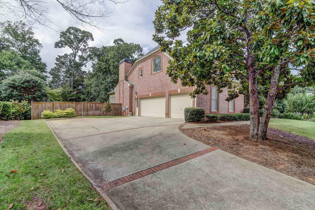 a large brick house with a driveway and a tree