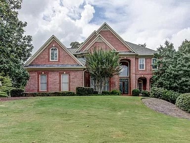 the front of a brick house with a large grass yard