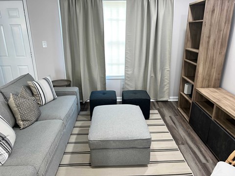 A living room with a grey couch and ottomans.