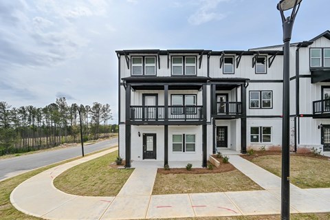 A black and white apartment building with a sidewalk and street light in front.