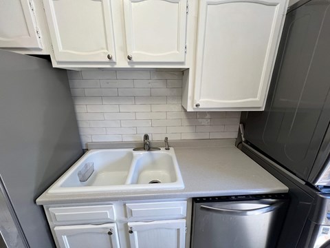 A kitchen with white cabinets and a white sink.
