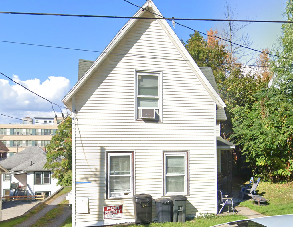 A house with a "For Rent" sign in front of it.