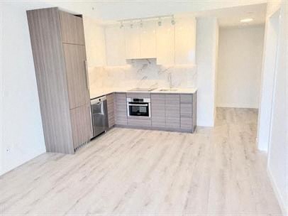 a white kitchen with a wooden floor and a refrigerator