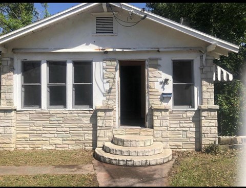 an old stone house with a front porch and steps