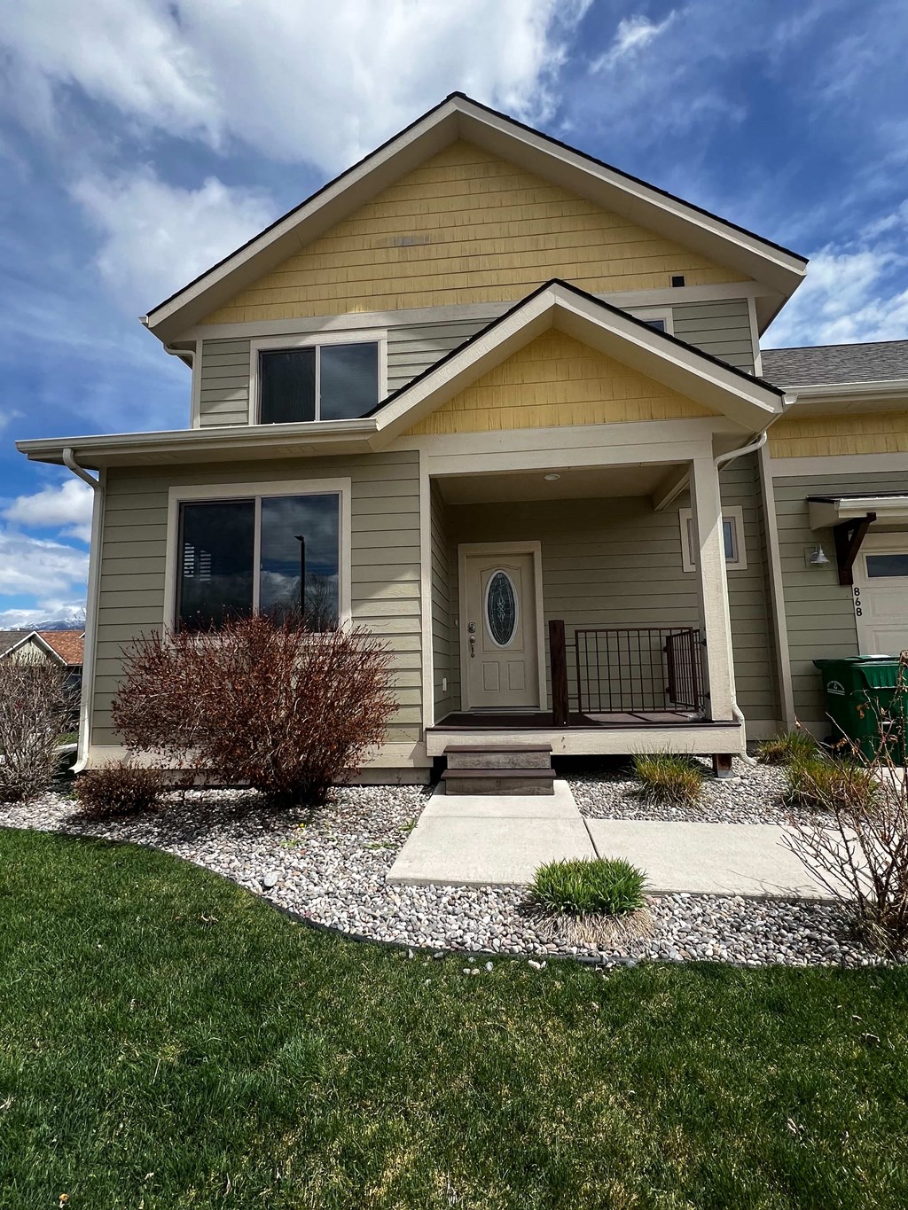 a tan house with a front porch and a lawn