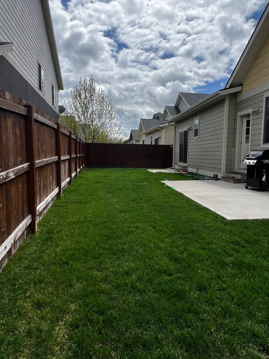 a backyard with a fence and a green lawn