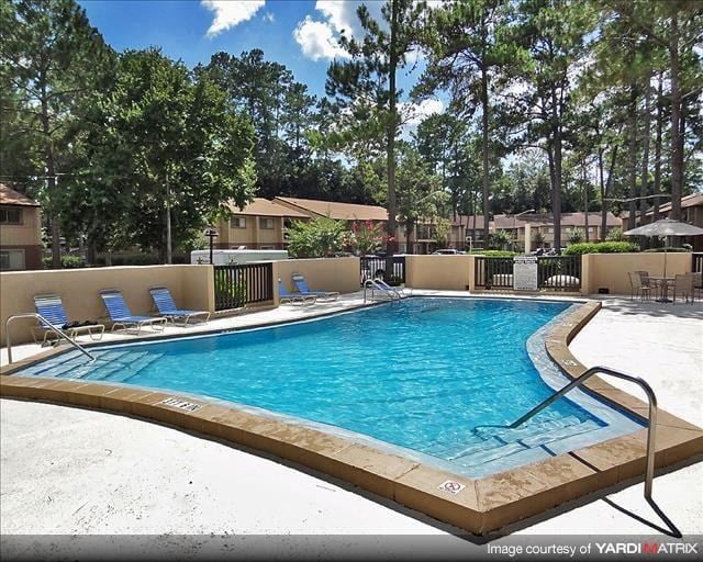 a large swimming pool with blue chairs and trees
