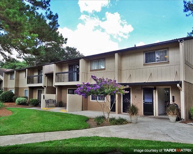an apartment building with a flowering tree in the yard