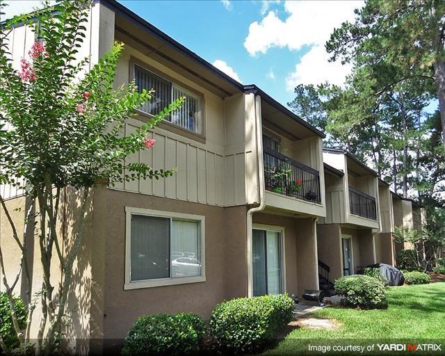 a brown apartment building with trees and bushes