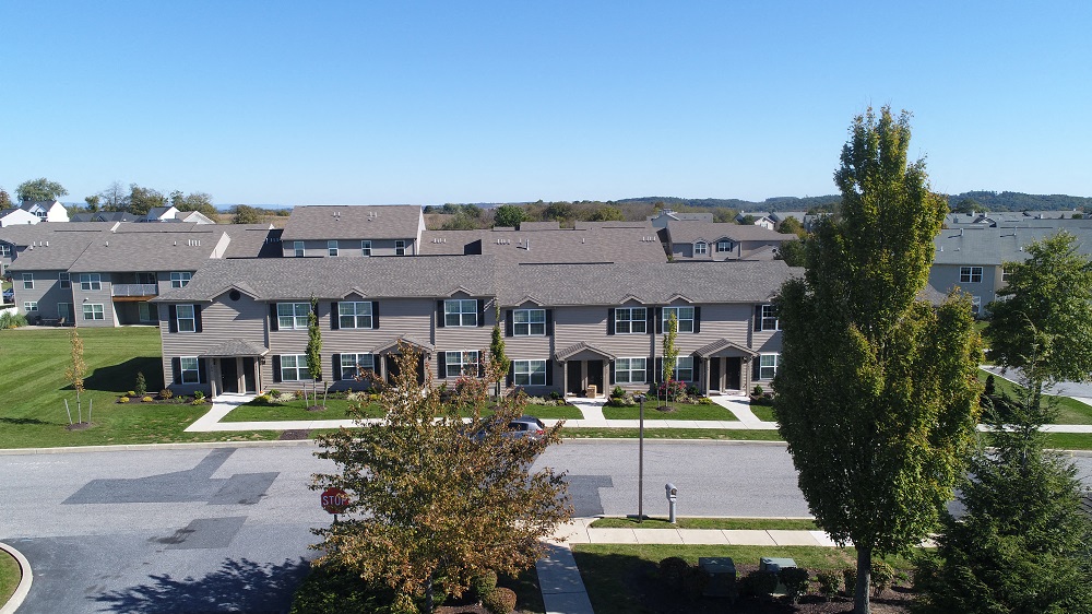 an aerial view of an apartment complex with a street and trees